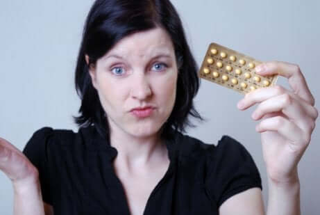 Une femme tenant une pilule contraceptive.