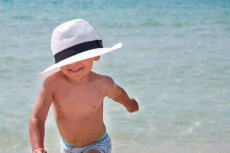 Un enfant avec un chapeau à la plage.