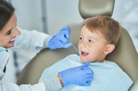 Une dentiste qui passe le fil dentaire dans la bouche d'un enfant. 