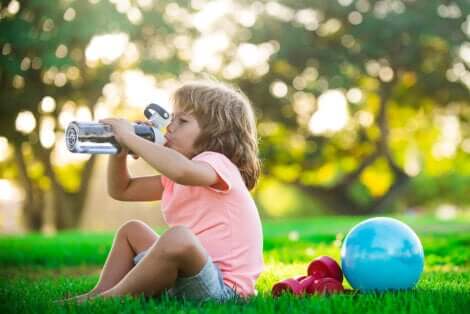 Une enfant qui boit de l'eau après avoir fait du sport.