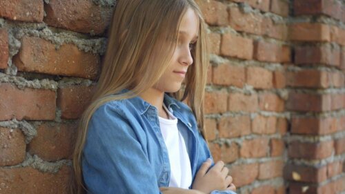 Une fille solitaire contre un mur de briques.