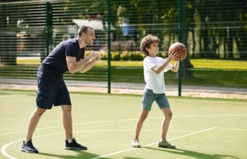 Un père qui apprend à son fils à jouer au basket. 