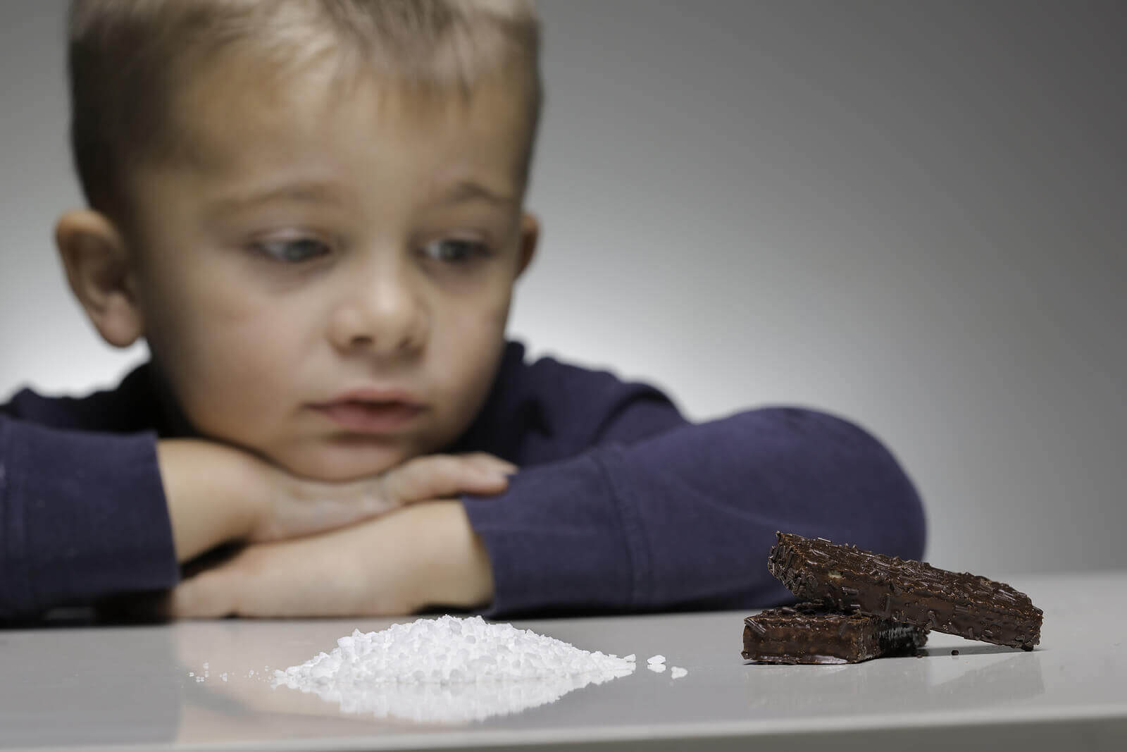 Un enfant regardant du sucre et du chocolat.