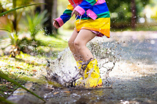 Un enfant qui saute dans une flaque d'eau et de boue.