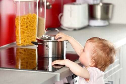 Un enfant qui touche une casserole sur les plaques de cuisson. 