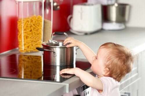 Un enfant qui touche une casserole sur les plaques de cuisson.