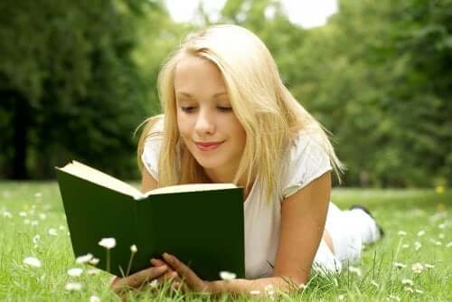 Une fille qui lit un livre dans un champ.