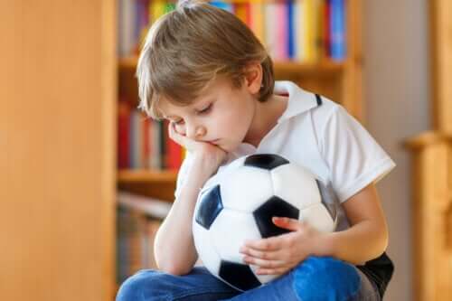 Garçon triste avec un ballon de football.