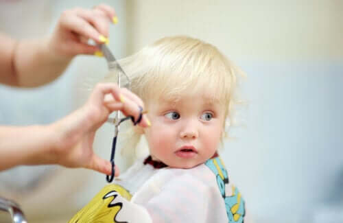 première coupe de cheveux coiffeur bébé garçon ciseaux peigne salon cape chaise barbier main