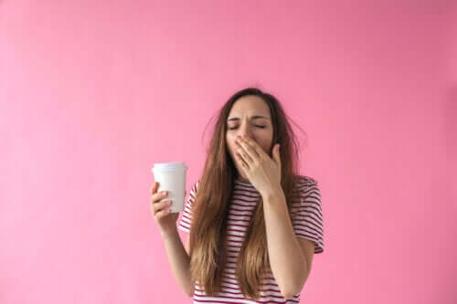 adolescent avec un verre de café à la main bâille endormi fatigué