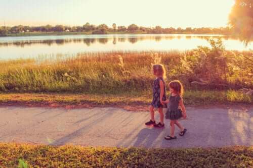 des filles heureuses marchent le long du chemin du parc à côté de la rivière