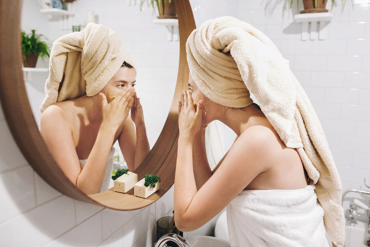 Une femme devant un miroir qui fait un soin du visage.