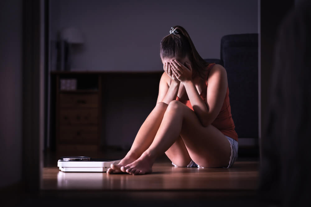 femme pleurant sur le sol devant sa balance