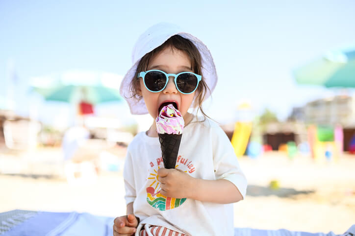 petite fille avec des lunettes mangeant une glace à la plage