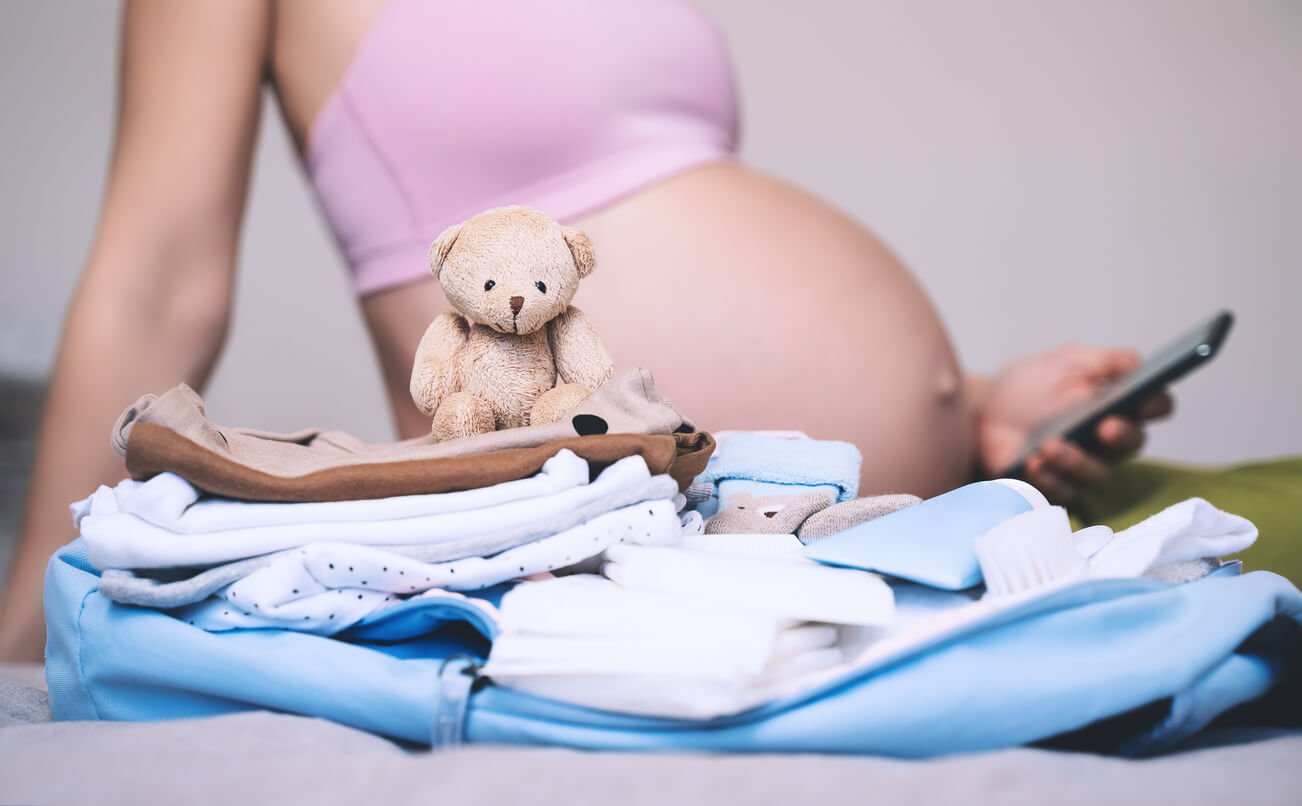 femme enceinte devant des vêtements pour bébé