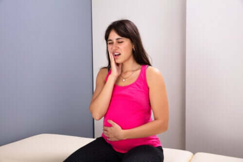 Pregnant woman sitting on bed brancard main sur joue mal de dents