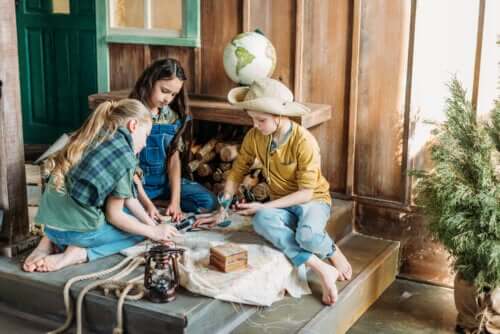 les enfants sur le porche de la maison jouent à la chasse au trésor avec une carte et des lampes à huile