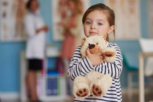 petite fille étreint son ours dans le bureau du médecin mère et médecin en arrière-plan