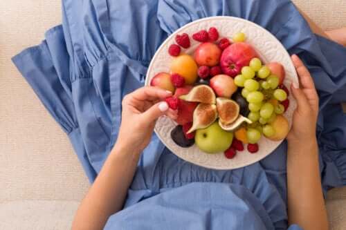 mains de jeune fille avec une assiette de fruits sur sa jupe