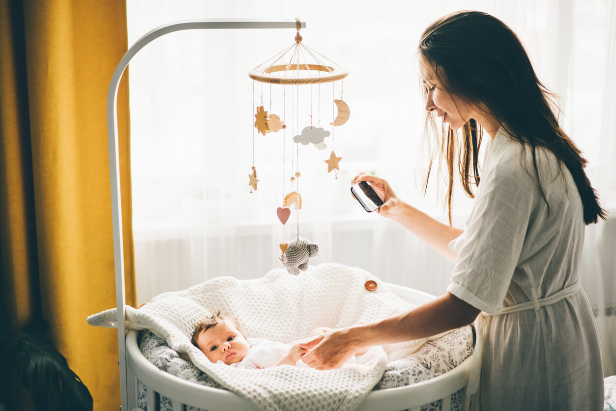 mère prenant son bébé en photo dans son berceau