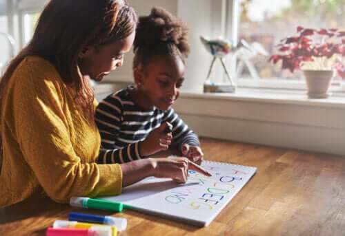 mère enseignante enseignant les lettres de l'alphabet lisant à l'écolière