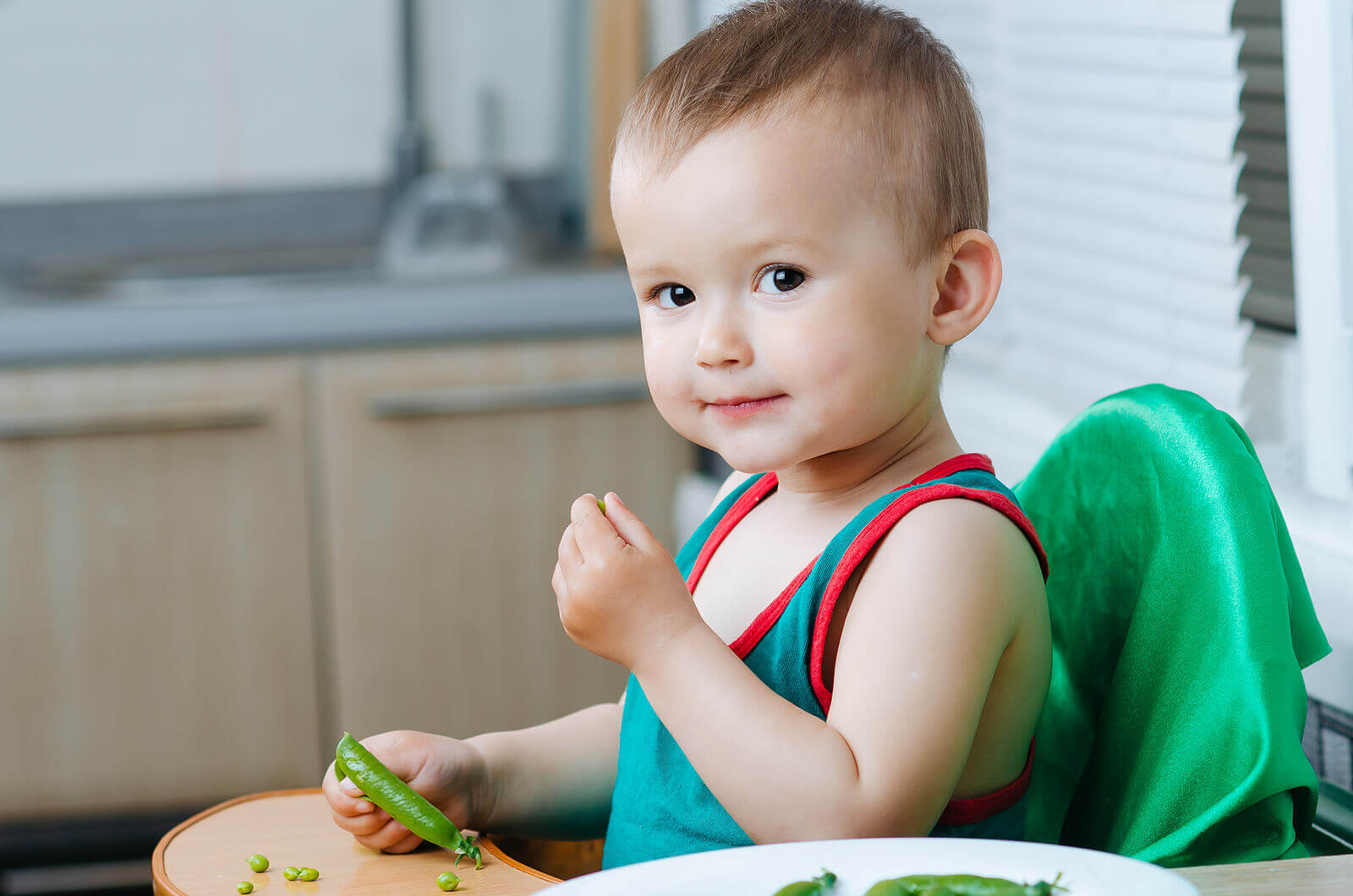 Un enfant qui mange des petits pois.