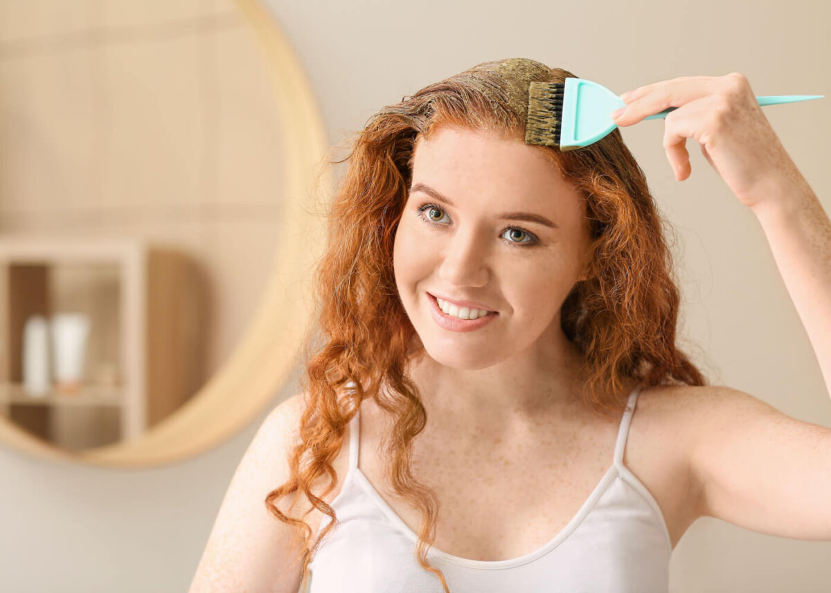 femme rousse appliquant du henné sur ses cheveux