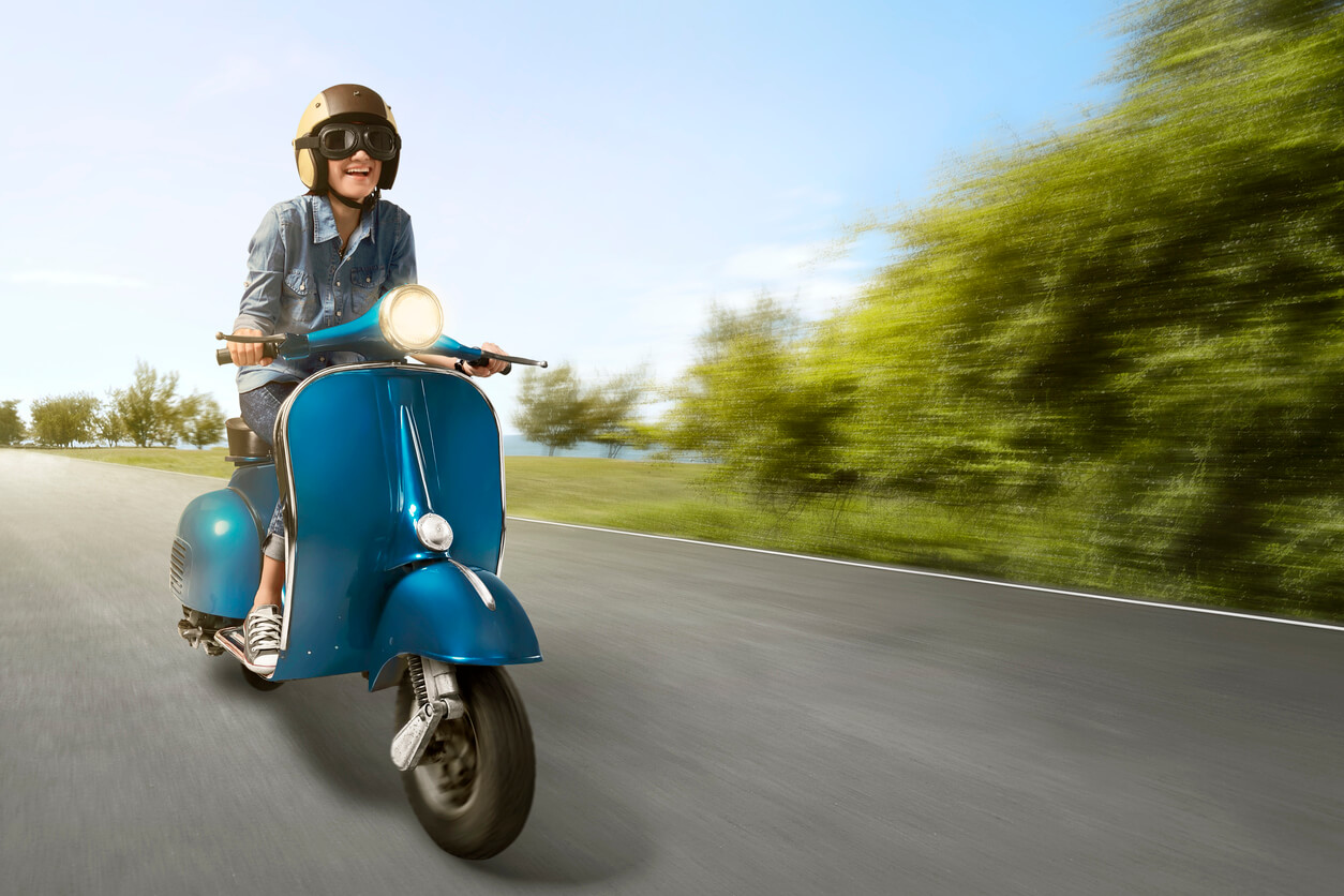 Heureuse femme asiatique faisant du scooter à grande vitesse dans la rue
